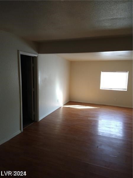 empty room featuring a textured ceiling and dark hardwood / wood-style flooring