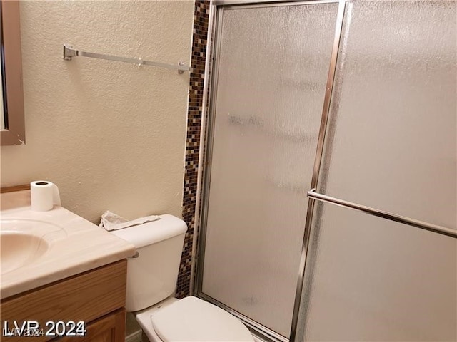 bathroom featuring vanity, a shower with shower door, and toilet