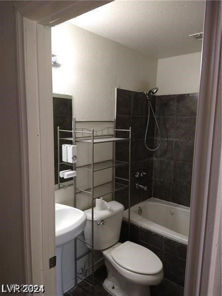 bathroom with toilet and tiled shower / bath