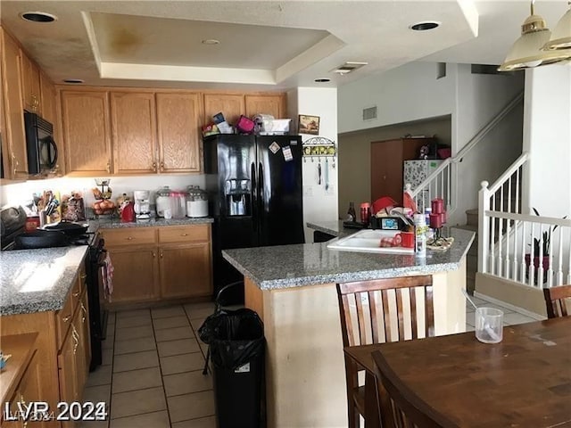 kitchen featuring sink, light stone counters, black appliances, and a tray ceiling