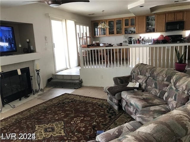 living room featuring ceiling fan and a tile fireplace