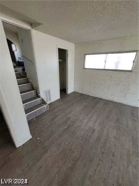 interior space with a textured ceiling and dark hardwood / wood-style flooring