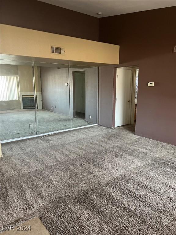 unfurnished bedroom featuring a closet, a high ceiling, carpet flooring, and multiple windows