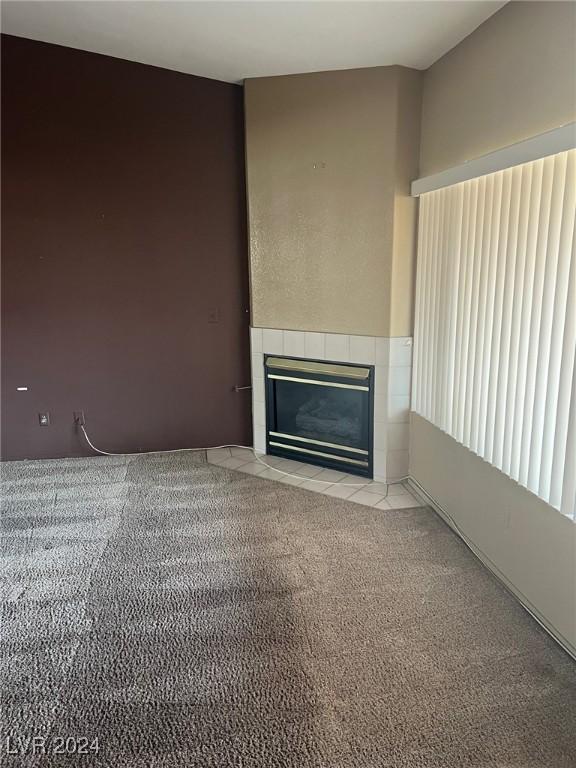 unfurnished living room with light carpet and a tile fireplace