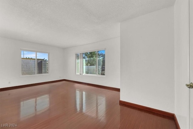 empty room with a textured ceiling and hardwood / wood-style flooring