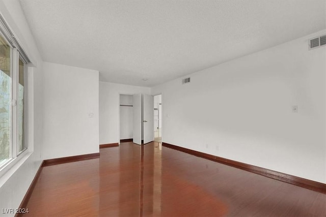 unfurnished room featuring a textured ceiling and dark wood-type flooring