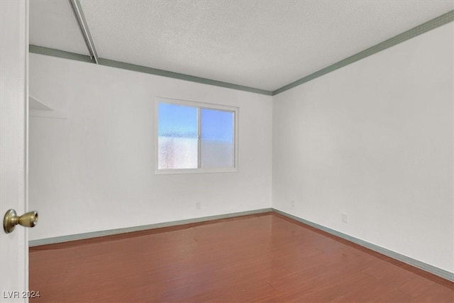 spare room with wood-type flooring, a textured ceiling, and crown molding