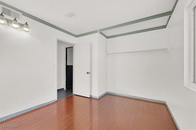 spare room with hardwood / wood-style floors, a textured ceiling, and ornamental molding