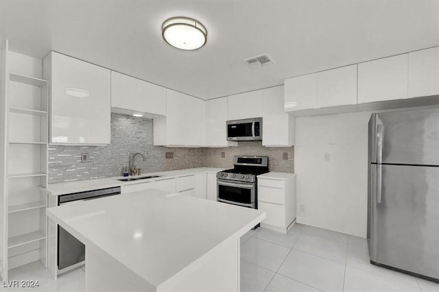 kitchen with backsplash, sink, a kitchen island, white cabinetry, and stainless steel appliances