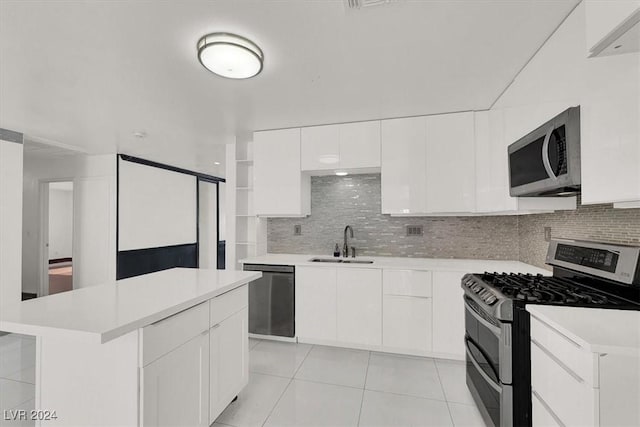 kitchen with white cabinetry, a center island, sink, stainless steel appliances, and backsplash