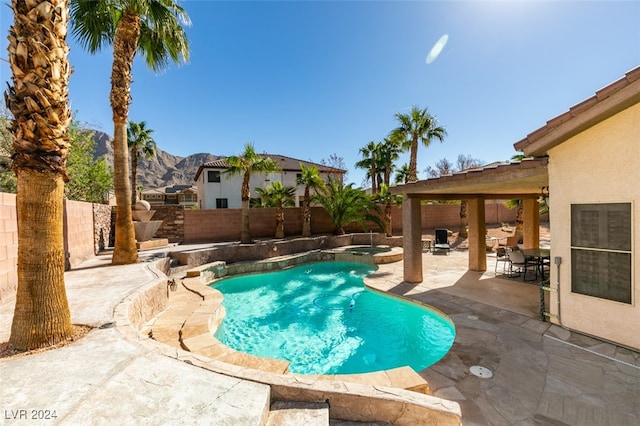 view of pool with a patio, an in ground hot tub, and a mountain view