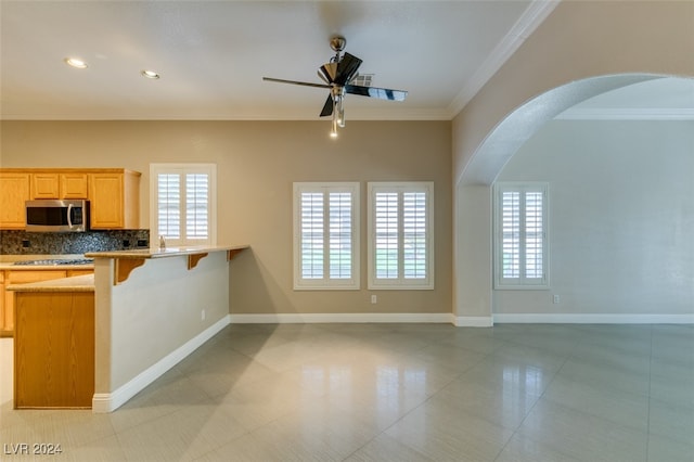 kitchen featuring backsplash, crown molding, a breakfast bar, and a wealth of natural light