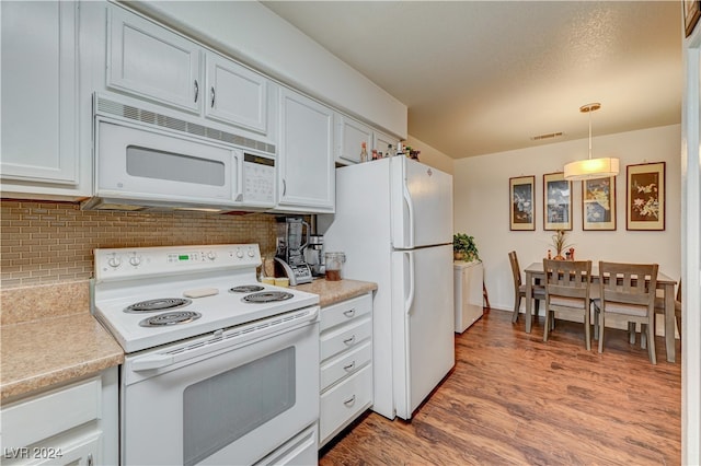 kitchen with white cabinets, decorative light fixtures, white appliances, and light hardwood / wood-style floors