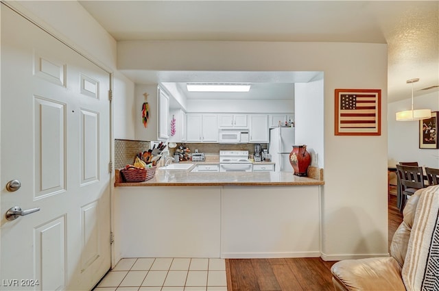 kitchen featuring white cabinets, backsplash, light wood-type flooring, sink, and white appliances