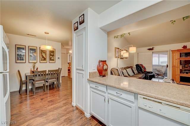 kitchen with lofted ceiling, white cabinetry, light wood-type flooring, decorative light fixtures, and white appliances