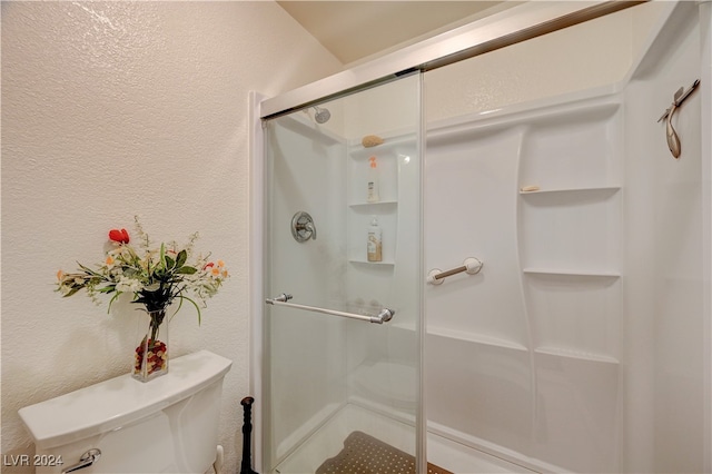 bathroom featuring toilet and a shower with shower door