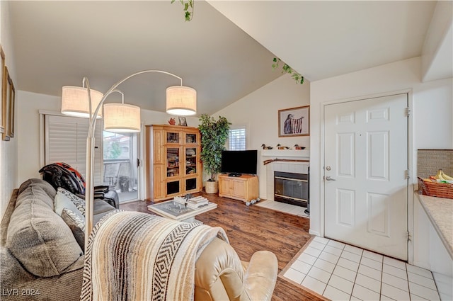 living room with light hardwood / wood-style flooring, lofted ceiling, a tile fireplace, and plenty of natural light