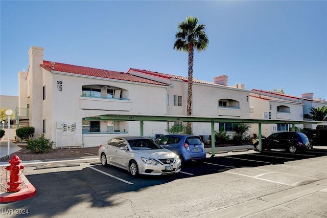 view of property featuring covered and uncovered parking