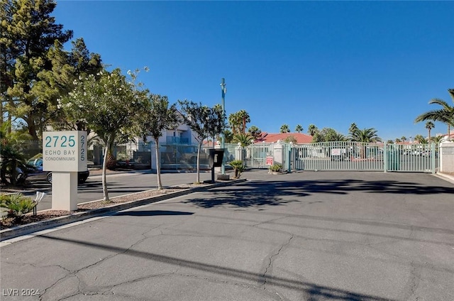 view of street featuring a gate, a gated entry, and curbs