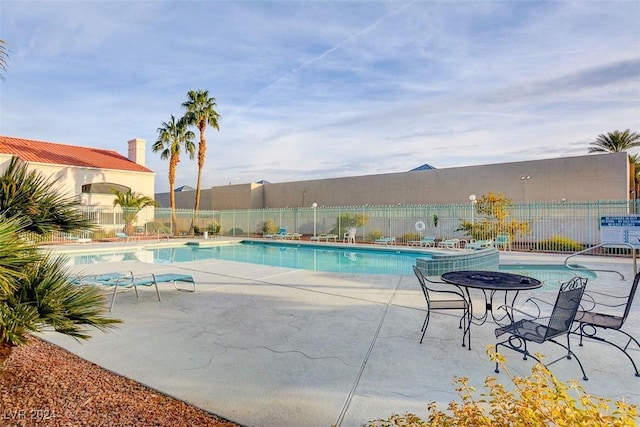 community pool with fence and a patio area