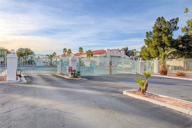 view of street with a gate, a gated entry, and curbs
