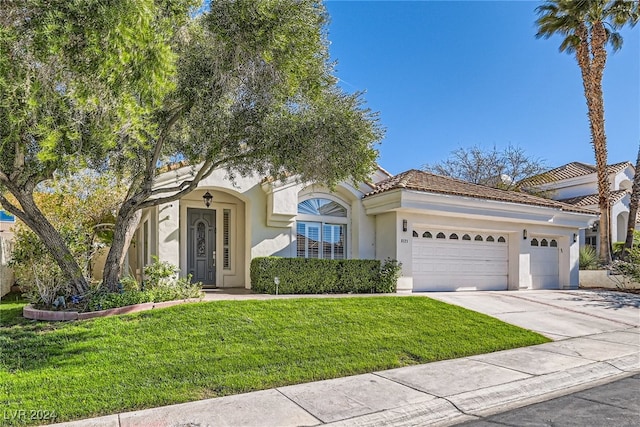 mediterranean / spanish-style house featuring a front yard and a garage