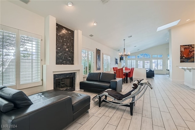 living room with light hardwood / wood-style flooring, a notable chandelier, lofted ceiling with skylight, and a healthy amount of sunlight