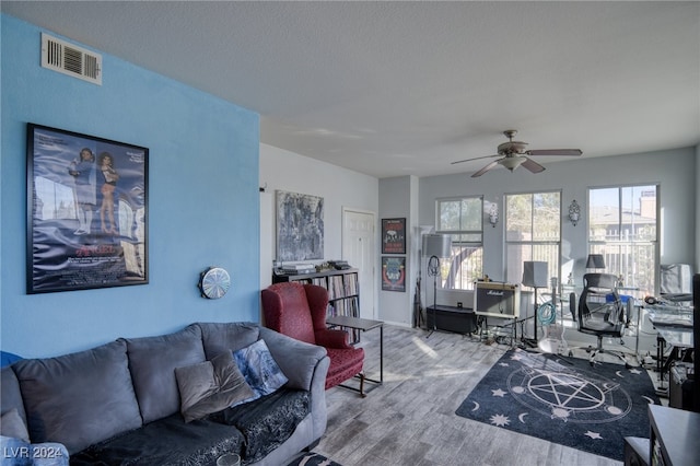 living room with a textured ceiling, hardwood / wood-style flooring, and ceiling fan