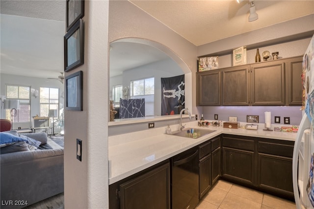 kitchen with black dishwasher, sink, a textured ceiling, and a healthy amount of sunlight