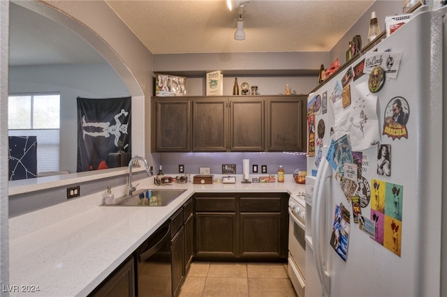 kitchen featuring dark brown cabinets, a textured ceiling, light tile patterned flooring, sink, and white appliances