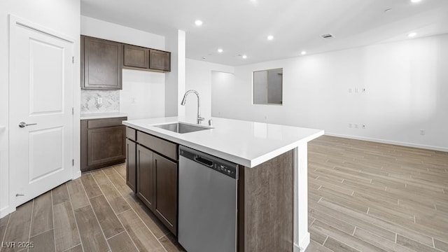 kitchen featuring light countertops, a kitchen island with sink, dishwasher, and a sink