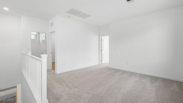 spare room featuring visible vents, light carpet, and baseboards