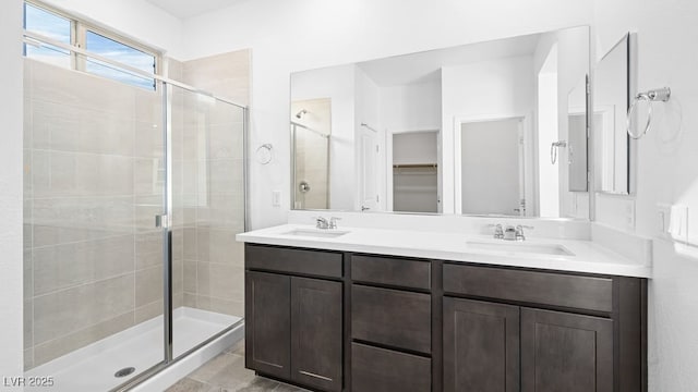 bathroom featuring a stall shower, a sink, and double vanity