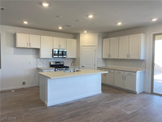 kitchen with an island with sink, stainless steel appliances, sink, and white cabinets