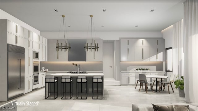 kitchen featuring sink, built in appliances, a kitchen island with sink, and white cabinets