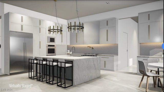 kitchen with a breakfast bar area, built in appliances, backsplash, sink, and a chandelier