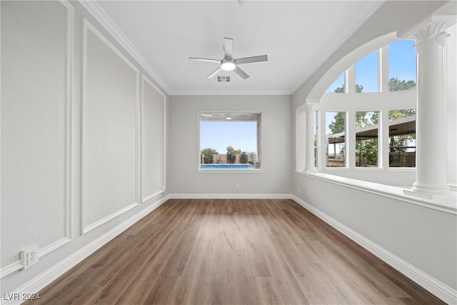 unfurnished room featuring visible vents, ornamental molding, a ceiling fan, wood finished floors, and ornate columns