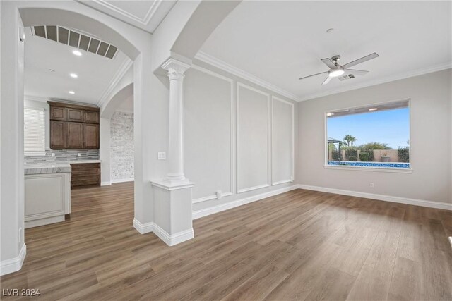 unfurnished living room featuring ceiling fan, dark hardwood / wood-style flooring, ornate columns, and ornamental molding