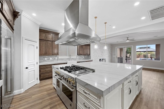 kitchen with light hardwood / wood-style flooring, island exhaust hood, a spacious island, double oven range, and white cabinets