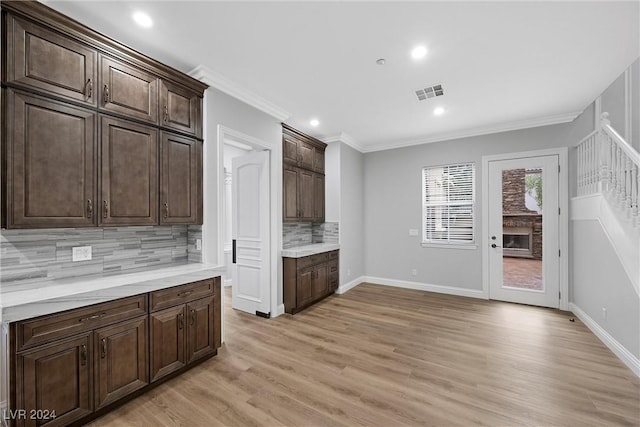 kitchen with dark brown cabinetry, crown molding, light hardwood / wood-style flooring, and decorative backsplash