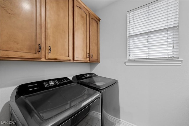 washroom featuring tile patterned flooring, cabinets, a wealth of natural light, and washing machine and clothes dryer