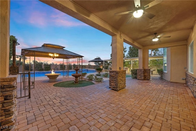 patio terrace at dusk featuring a gazebo and ceiling fan