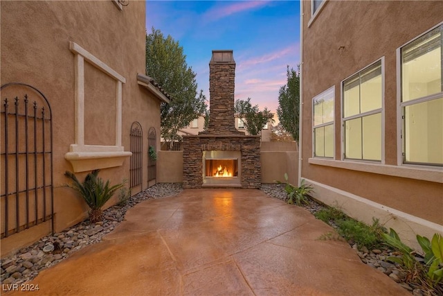 patio terrace at dusk featuring an outdoor stone fireplace