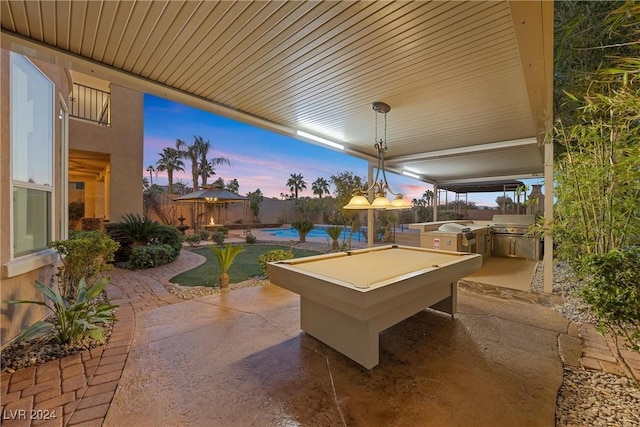 patio terrace at dusk with an outdoor kitchen, fence private yard, a fenced in pool, and a grill