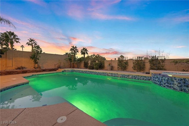 pool at dusk with an in ground hot tub