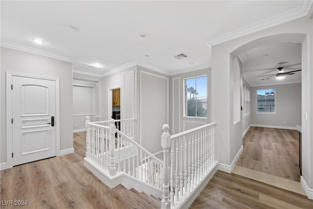 hallway with ornamental molding, visible vents, an upstairs landing, and wood finished floors