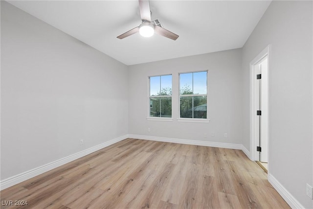 spare room with light wood-type flooring, baseboards, and a ceiling fan