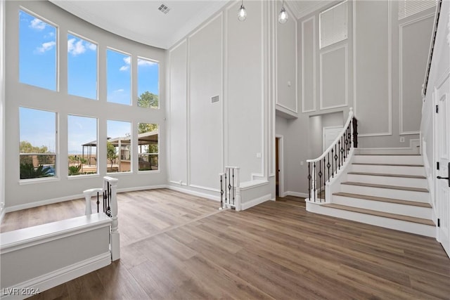 interior space featuring stairway, wood finished floors, visible vents, and a decorative wall