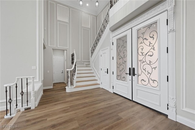 entryway with baseboards, stairway, wood finished floors, french doors, and a decorative wall