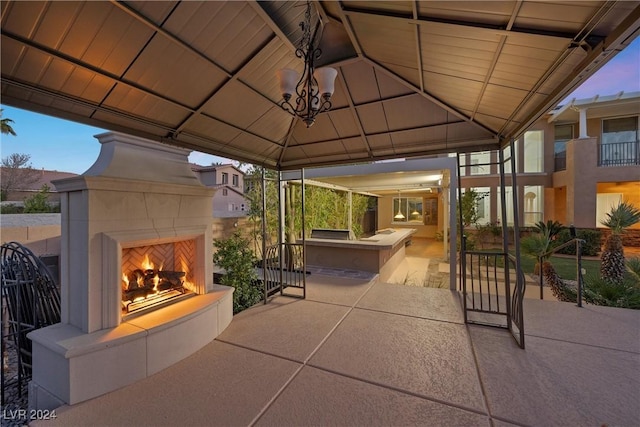 patio terrace at dusk featuring a gazebo and a tiled fireplace